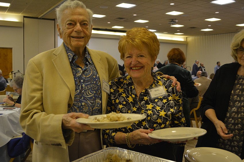Marvin Morse (left) and Betty Morse (right) pose while being served at a Sephardic-style feast Friday night at Temple Beth Israel.
