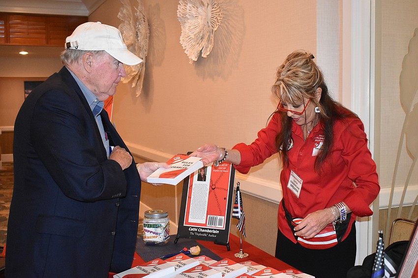 Cathi Chamberlain hands Glen Peterson a signed book.