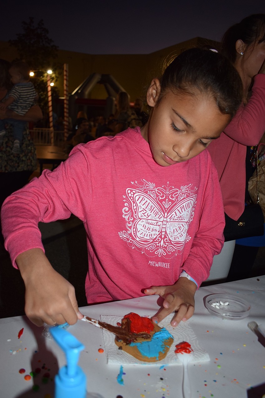 Iliana Chaviano, a third grader, decorates a cookie with blue, red and chocolate frosting.
