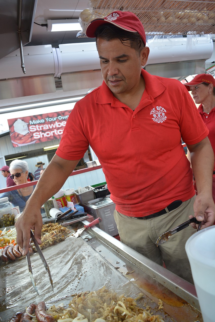 Chino Beltran, of  The Best Around, grills onions, peppers and sausages for the hungry crowd.