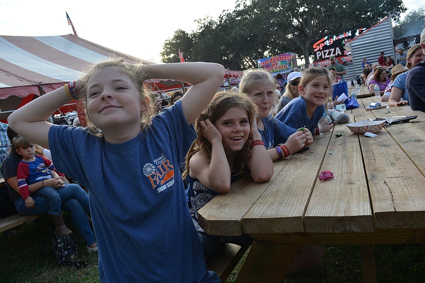 Myakka City's Adeline Allen, 11, with friend Kyria Stillman behind her, watches as Allen's brother, Isaiah Allen, competes in a corn dog eating contest.