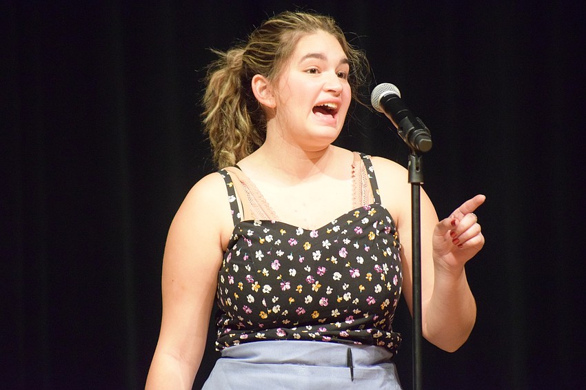Dressed as a waitress, Emily Garcia sings 