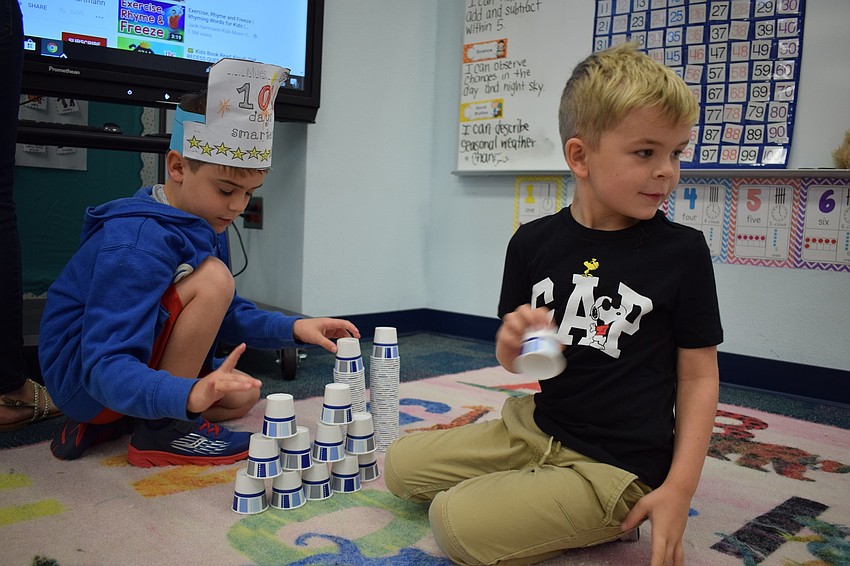 Kindergartners Miles Huggins and Charlie Price build a tower out of 100 small paper cups.