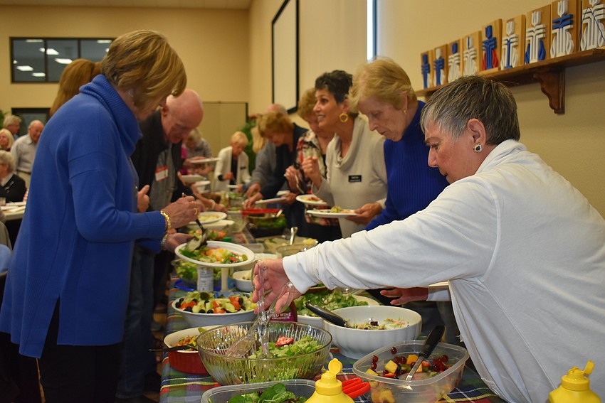Attendees selected from a spread of salads and other side dishes, plus ham.