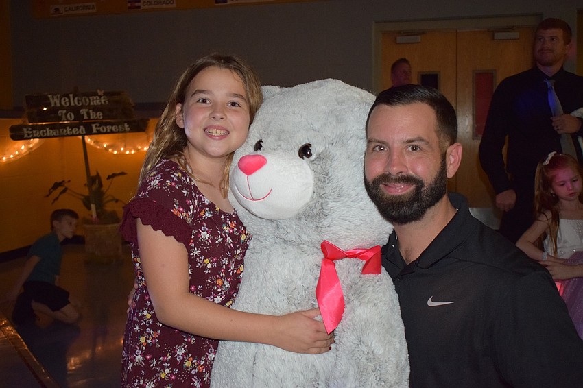 Ava Delvin, a fourth grader, and her dad, Tim, win a giant teddy bear in a raffle. 