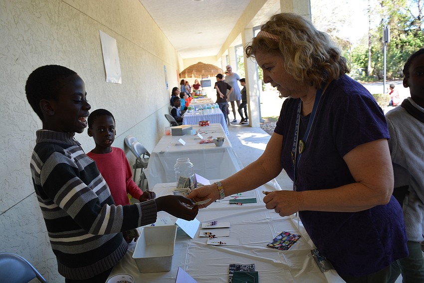 Longboat Key's Peter M'Mwirichia sells a wallet to Braden River Library Youth Services Librarian Chris Culp. M'Mwirichia also sold beaded earrings.
