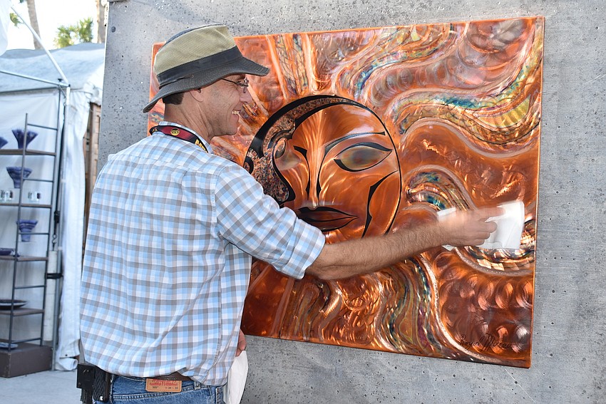Royal Miree dusts off one of his copper panels.