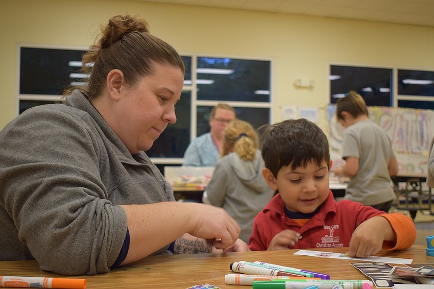 Elizabeth Zehr helps her 3-year-old son GeorgeHenry Hernandez put stickers on a bookmark. Hernandez attends literacy night with his sisters Vivian Figueroa, a third grader, and Alexandra Hernandez, a kindergartner.