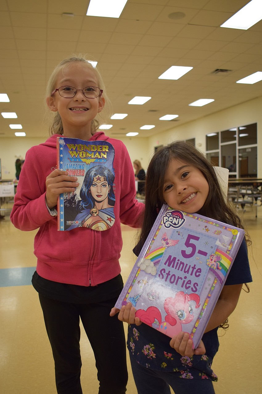 E'Lyiah Cruz, a second grader, and Lilliana Christie, who is 4, take home free books after completing six reading activities.