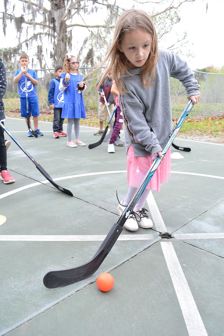 Second grader Audriana Eck learns she needs to keep the ball close to the hockey stick so it does not roll away and out of her control.