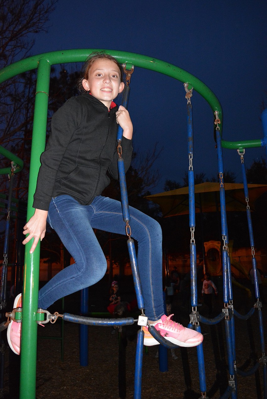 Fifth grader Ryann Gurski likes the bonfire, but makes time to climb around at the playground.