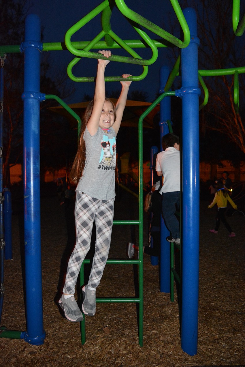 Six-year-old Maggie Neary tests her skills on the monkey bars amongst friends.