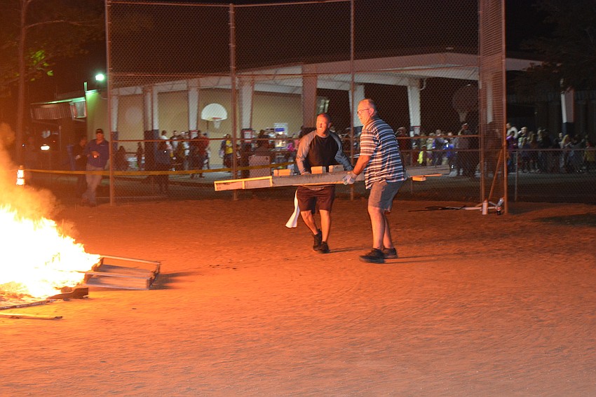 Coach Eric Boso and volunteer Tom Weatherly add pallets to fuel the fire. An estimated 200 pallets were used throughout the night.