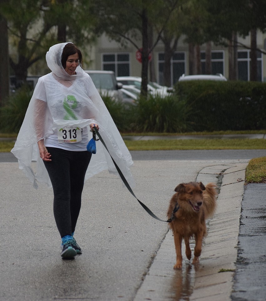 Lakewood Ranch's Laura Dardy walks in the rain with her dog, Toby. 