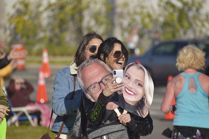 Debbie Peilet stands on the sidewalk as she waits for her family to run by.