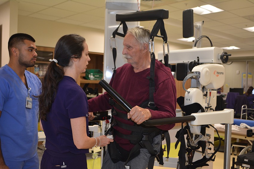 Stroke patient Ronald Serres (right) prepares to begin walking on the Hocoma Lokomat with the assistance of physical therapist Dr. Julia Figueroa (center) and rehab tech Daniel Gonzalez.