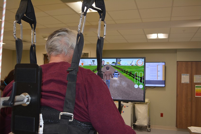Ronald Serres, a stroke patient, smiles as he plays a game on the Hocoma Lokomat. The Lokomat controls the amount of weight Serres feels on both sides, allowing him to practice walking while he regains use of the left of his body.