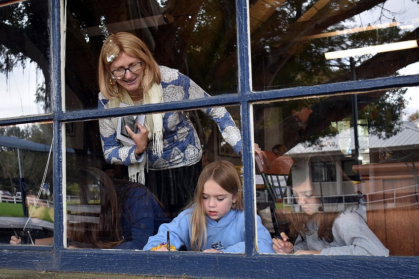 Martha Gulácsy helsp fourth grade students Isla Paterson and Amara Oliva with an assignment in the school's historic cabin.