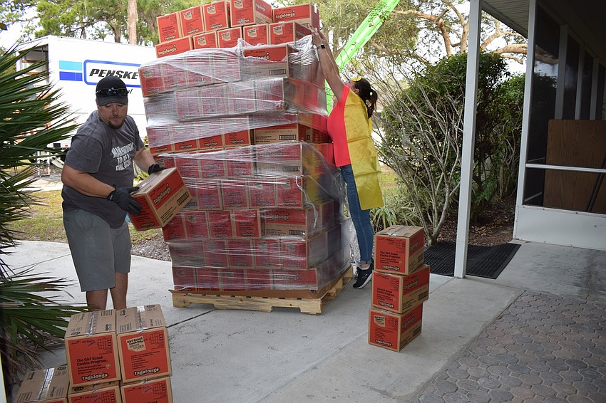 Volunteer Paul Wade and Aleksandra Moore, service unit cookie coordinator, take off the top two layers of cookies so the palette can fit through the doors of the building.