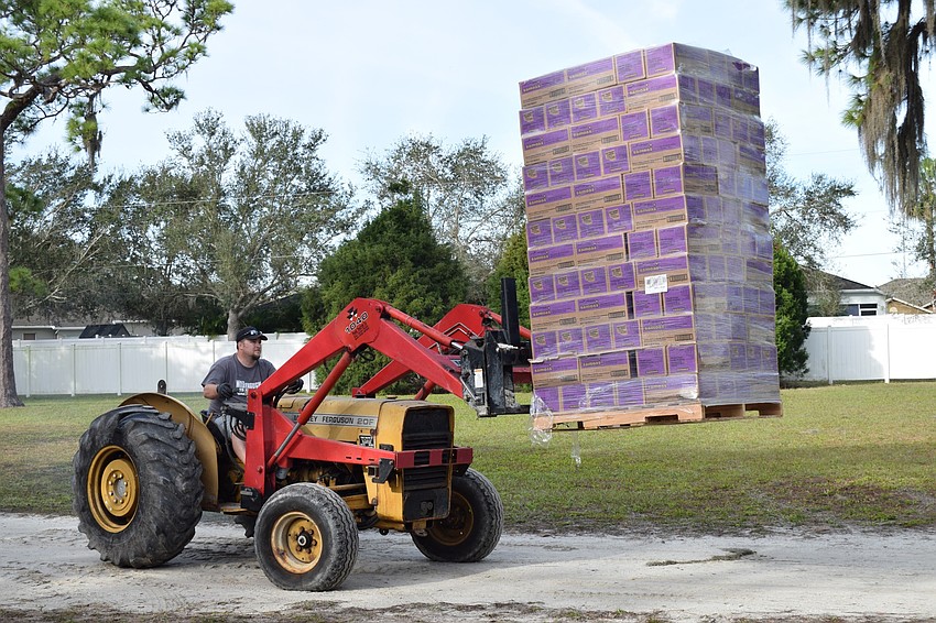 Paul Wade, a volunteer, uses a tractor to unload a palette of Samoas from a truck.
