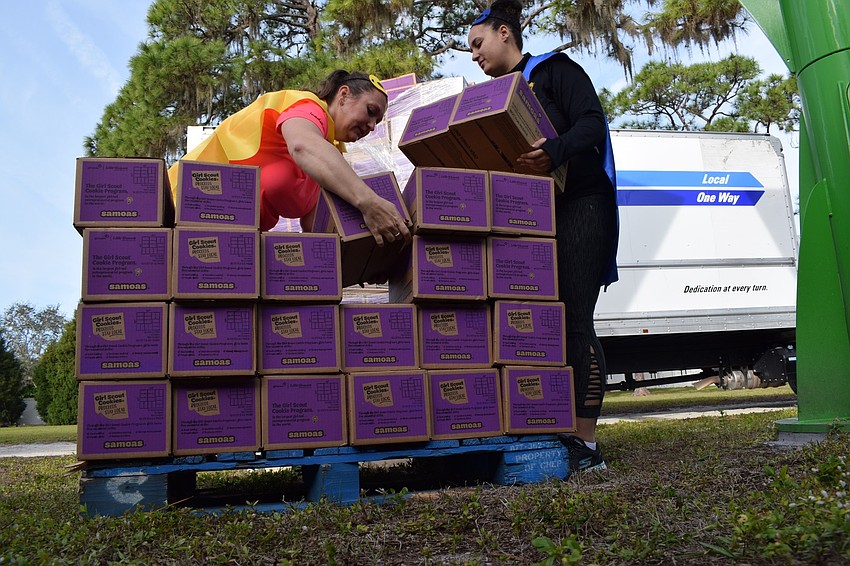 Aleksandra Moore, service unit cookie coordinator, and Sasha Lioce, product program manager, organize dozens of Samoas on a palette to be more easily moved into the building for distribution.