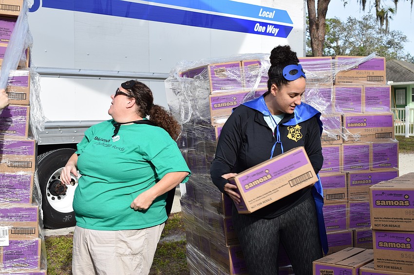 Erika Rolando, service unit manager, and Sasha Lioce, product program manager, work together to remove and organize cases of Samoas so the palettes can fit through the doors.