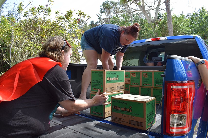 Amber Hill, who is the leader of Girl Scout Troop 7 and Troop 111, helps Brittney Pascoe, leader of Girl Scout Troop 34, load Thin Mints into the bed of a truck.