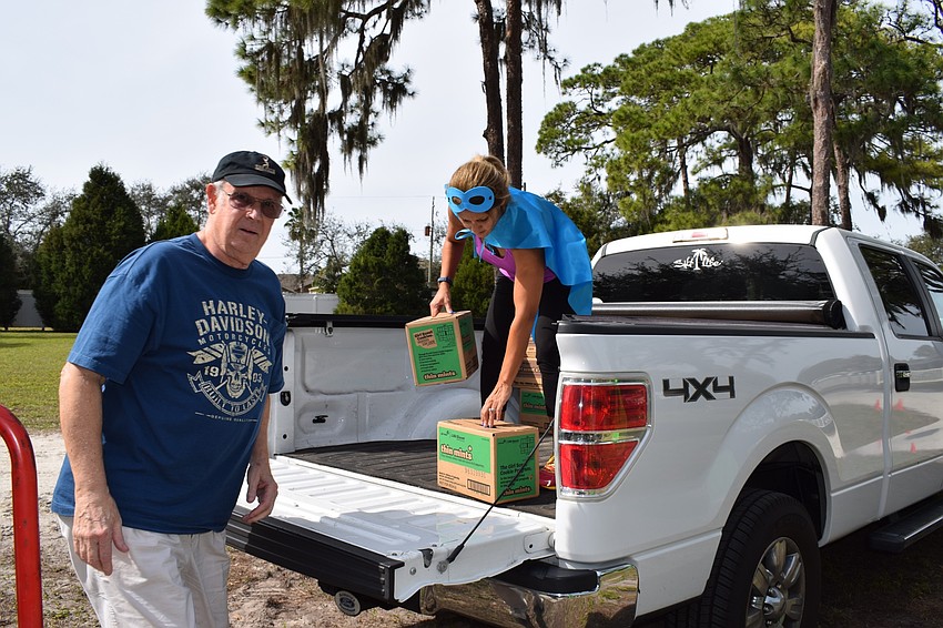 Richard Wood helps his daughter-in-law Nadia Wood, who is leader of Girl Scout Troops 885 and 26, load cookies onto the bed of a truck. 