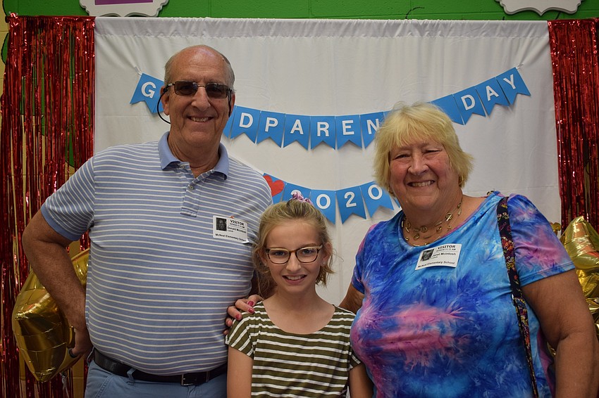 Donald McIntosh takes a photo with his granddaughter Savannah McIntosh, a fifth grader, and wife, Janet McIntosh, in front of a photo background made specially for Grandparents Day.