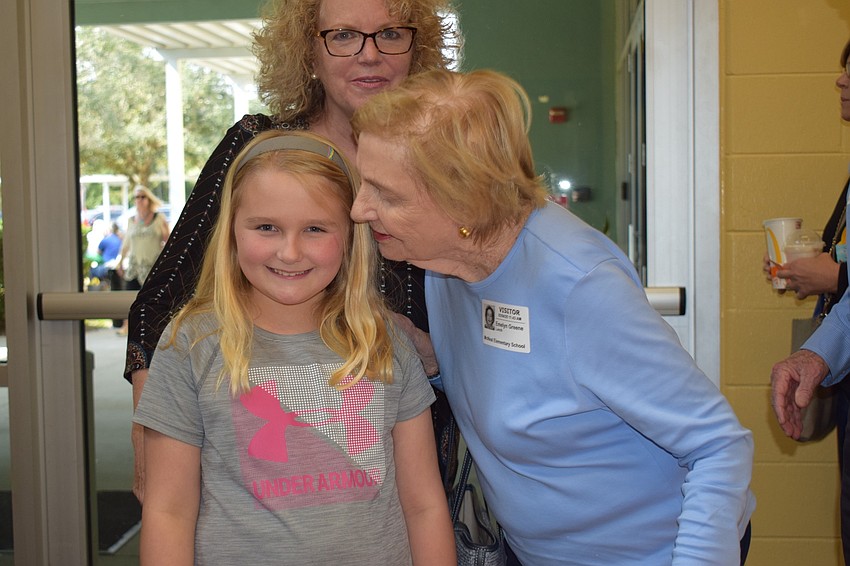 Sarah Overby, a fourth grader, smiles while her aunt, Katherine Tremblay (back) and grandmother Lyn Greene greet her.