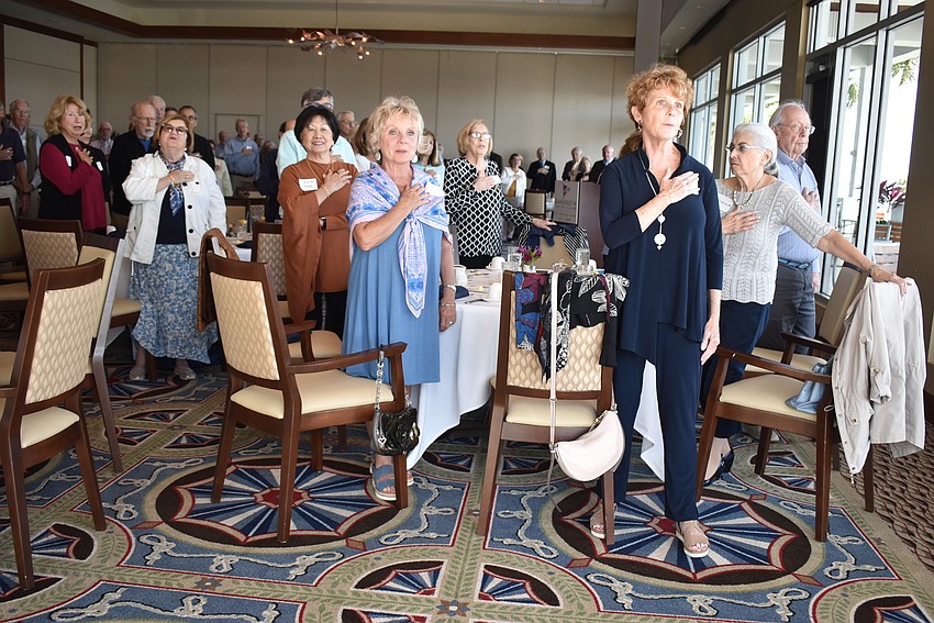 Attendees stand for the Pledge of Allegiance before the meeting.