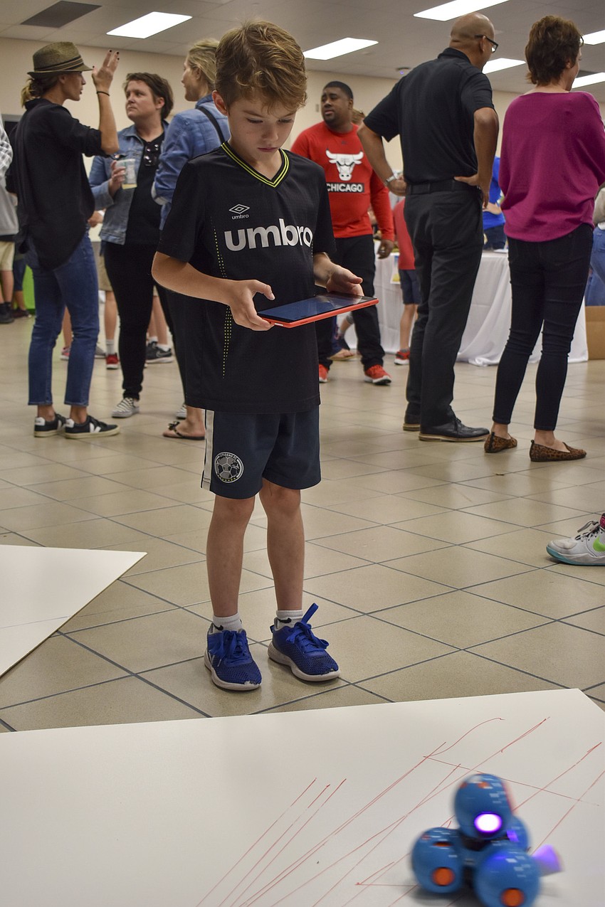 Mackie Bass, 6, plays with a robot.