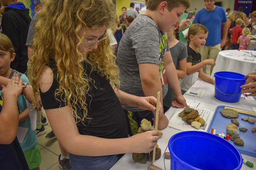 Piper Mulligan, 9, measures her rock tower.