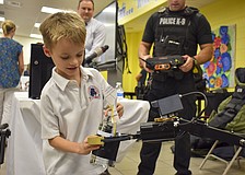 William Johnson, 6, passes a water bottle to a police robot.