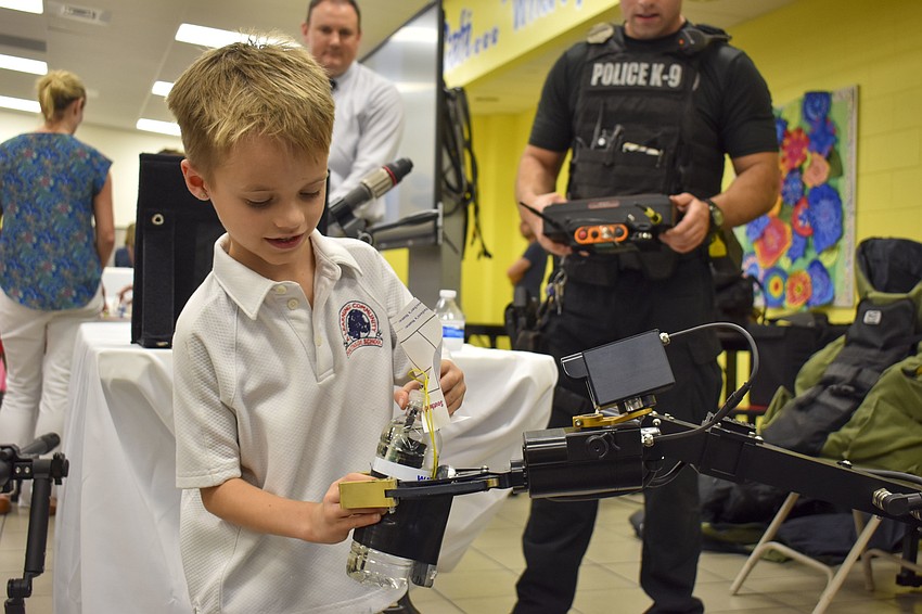 William Johnson, 6, passes a water bottle to a police robot.
