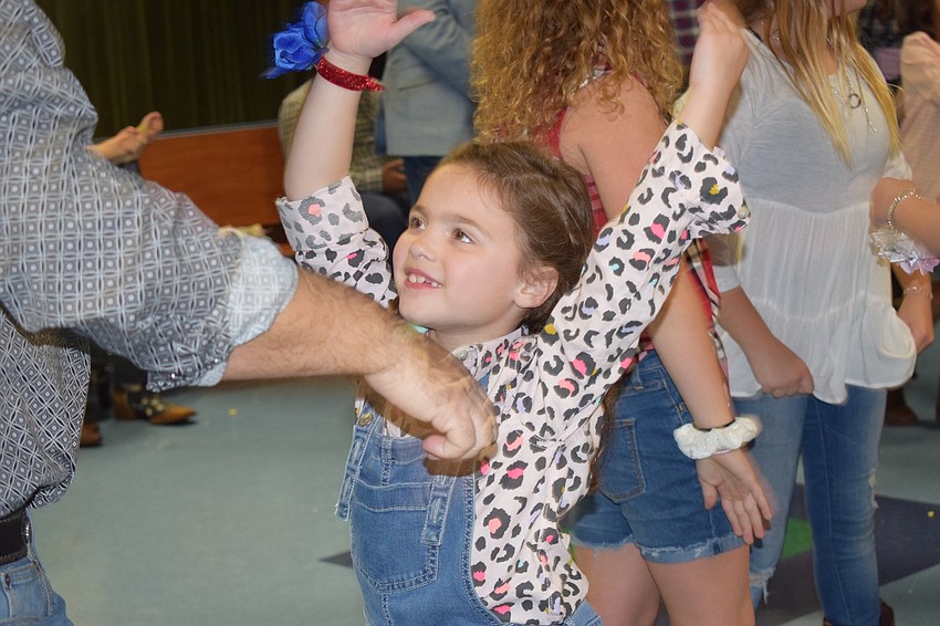 Abigail Rodriguez, a first grader, puts her hands into a 'y' formation while dancing to the 
