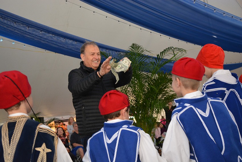 Kosta Maravelas throws dollar bills at his grandsons, Georgios and John Cappllouti,  as they demonstrate a Hellenic dance. Doing so symbolizes blessings of happiness.