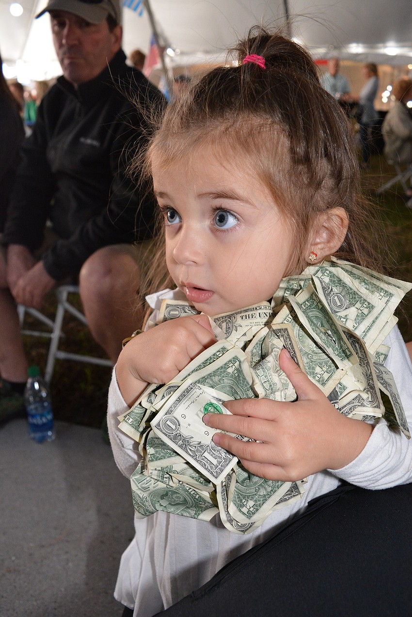 Three-year-old Magdalena Nicolaides scoops up money tossed over Hellenic dancers. Her mother, Joanna Nicolaides, is a dance instructor and the money will go toward the children's dance program and costumes.