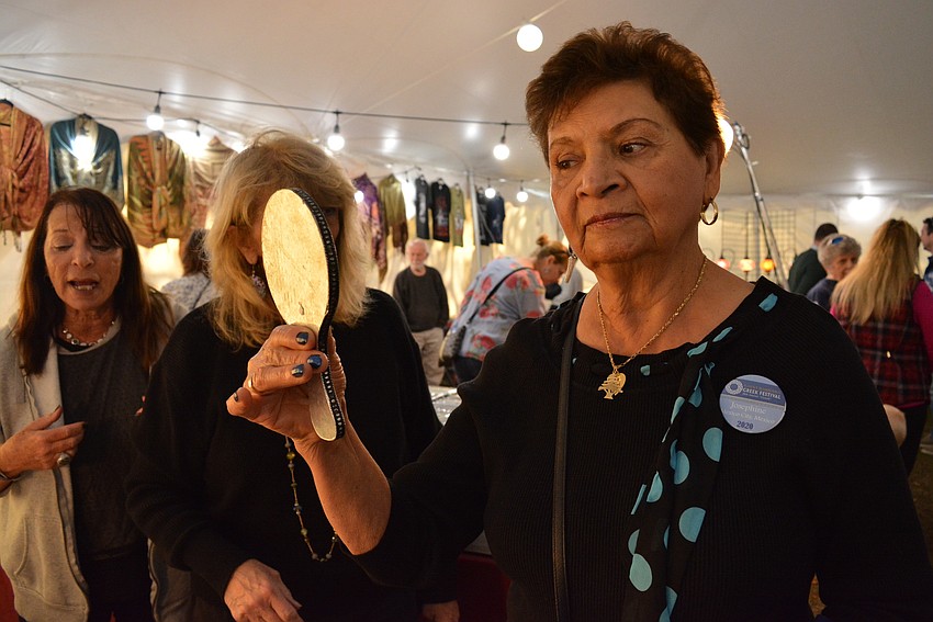 St. Barbara Greek Orthodox Church member and Glendi volunteer Josephine Fayad tries on some blue-and-white earrings at a vendor booth.