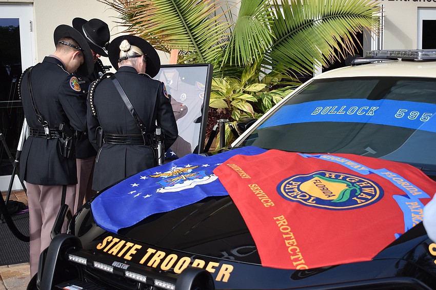 Law enforcement officers say a prayer in front of a frame containing Trooper Joseph Bullock's uniform.