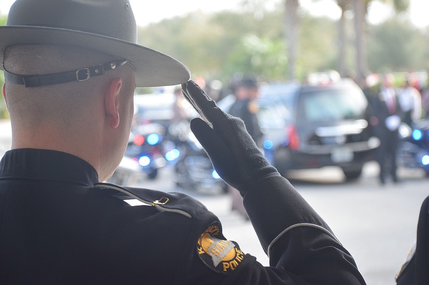 Law enforcement officers stand and salute as the casket of Trooper Joseph Bullock is brought to Bayside Community Church.