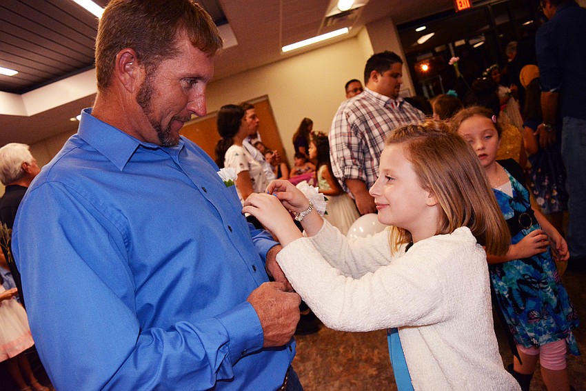 Nine-year-old Kannon Dougal, right, puts a carnation in the pocket of her father, Timmy Dougal. He bought her a wrist corsage for the dance.
