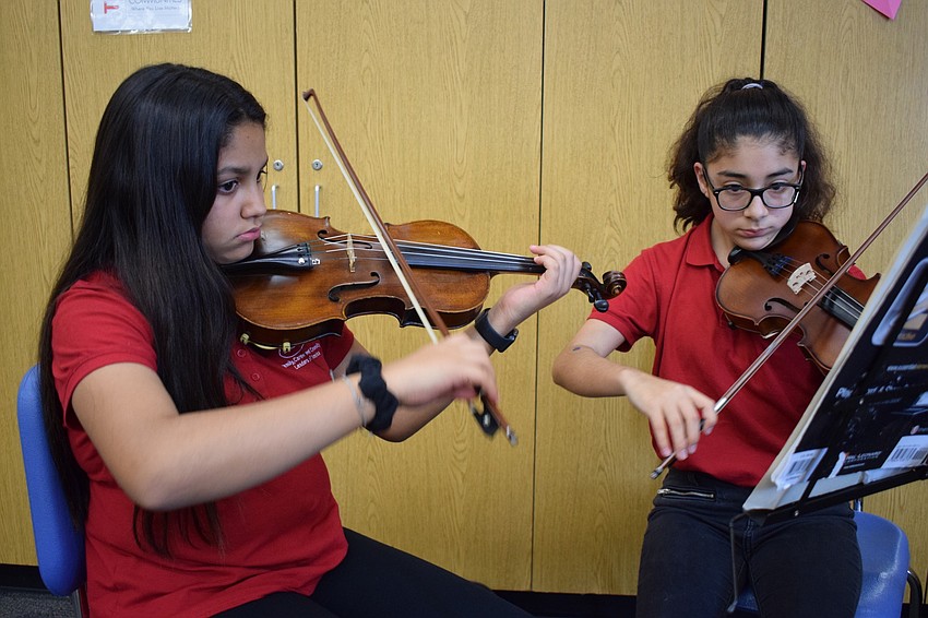 Eighth graders Victoria Oliveira and Andrea Mondragon play a violin duet during the Empty Bowls dinner.