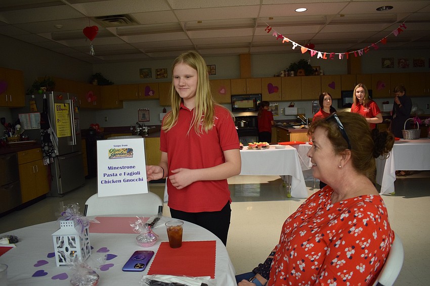 Makenna Bradley, an eighth grader and Family Career and Community Leaders of America member, shows Andrea Rath the soup options available.