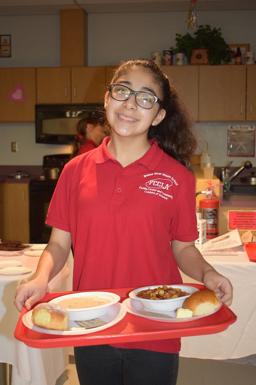 Andrea Mondragon, an eighth grader, carefully carries bowls of soup to serve to guests.