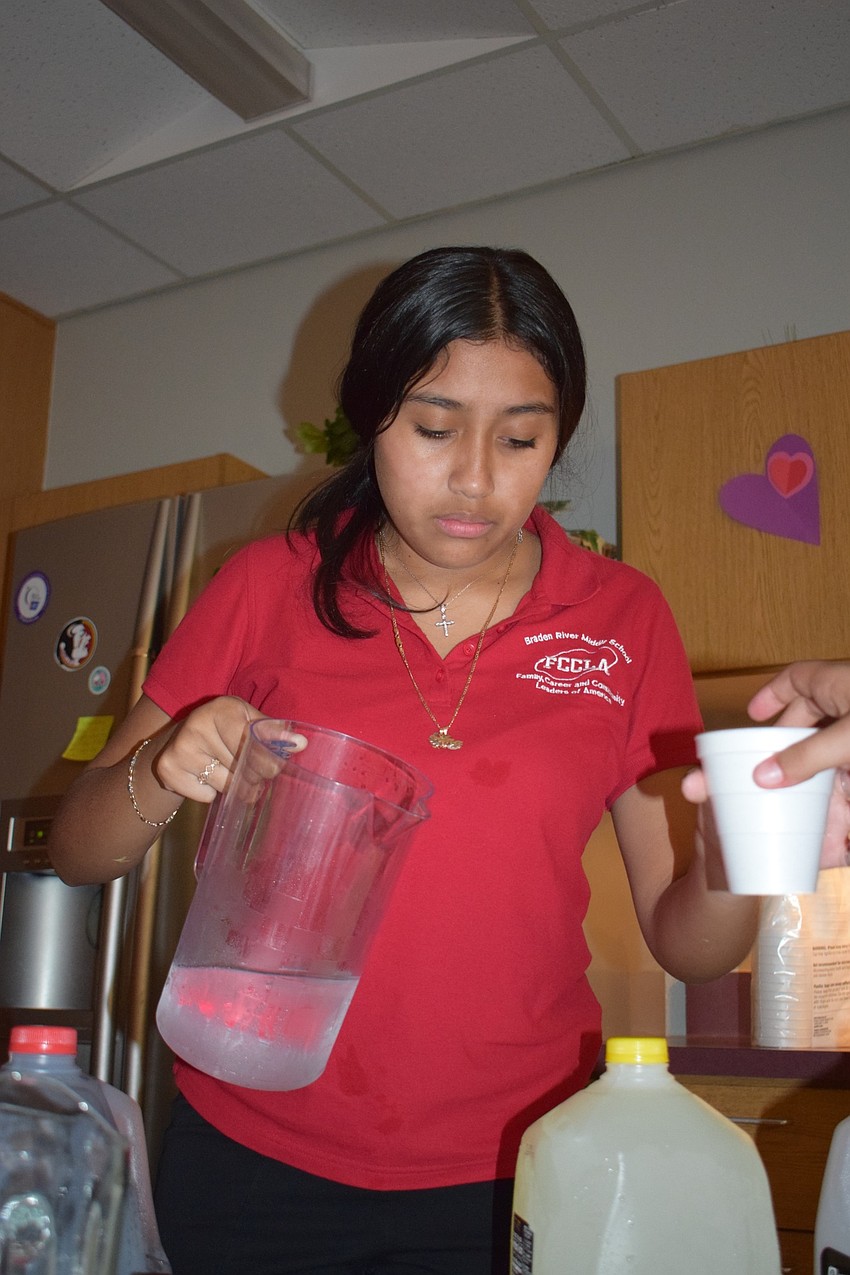 Edna Diaz, an eighth grader, pours drinks for guests at Empty Bowls. This is Diaz's first year in Family Career and Community Leaders of America.