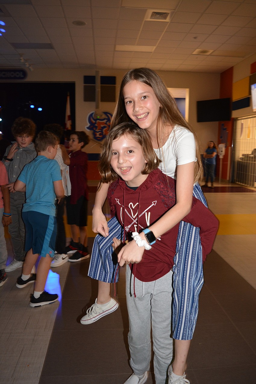Maya Gilkison gets a piggyback ride from friend Caitlin Conley after they finish dancing.