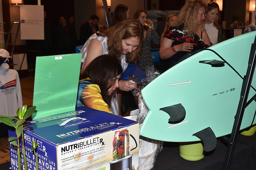Cynthia Collawn and Tricia Arslaner look at auction items.