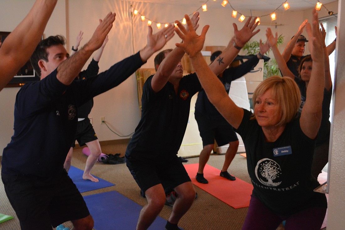 Debby McClung (right foreground) leads Longboat Key firefighters in a yoga pose Jan. 30.