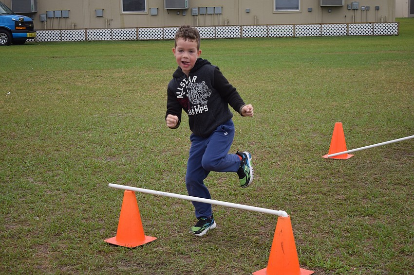 Liam Odendal, a kindergartner, jumps over a hurdle during his eighth lap of the walkathon.
